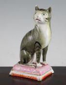 A Staffordshire pottery figure of a seated cat, c.1900, with tabby markings, seated upon a pink