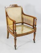 A Sheraton revival satinwood bergere armchair, painted with floral decoration and classical