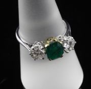 An 18ct two colour gold, emerald and diamond three stone ring, the central Columbian emerald