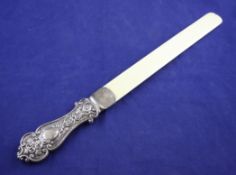 A late Victorian silver handled ivory page turner, the waisted handle embossed with foliate and