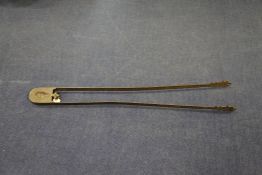 An unusual large pair of wrought iron ember tongs, with engraved decoration and a mythical beast