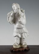 A Chinese white glazed porcelain figure of Shou Lao, holding a peach branch over his shoulder, on an