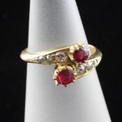 A late Victorian 18ct gold ruby and diamond cross over ring, with round cut rubies and three stone