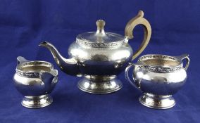 A George V Arts & Crafts planished silver three piece tea set by Albert Edward Jones, of inverted