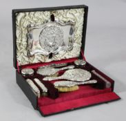 A cased Edwardian repousse silver ten piece dressing table set, comprising tray, three silver