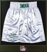 A pair of boxing trunks signed by Joe Frazier, the white shorts with green machine stitched