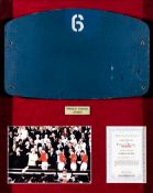 An old Wembley Stadium seat back numbered “6”, mounted in a deep frame together with a colour