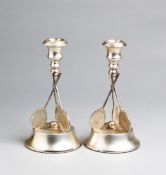 A pair of silver plated tennis candlesticks,
the candle holders supported on a ball resting on