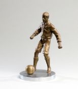 A bronze figure of a footballer, modelled with the ball at his feet, mounted on a circular steel