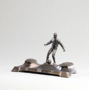 An Art Nouveau spelter football inkstand, surmounted with a figure of a footballer with the ball at