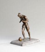 A bronze figure of a footballer,
modelled running with the ball at his feet, marble plinth, height