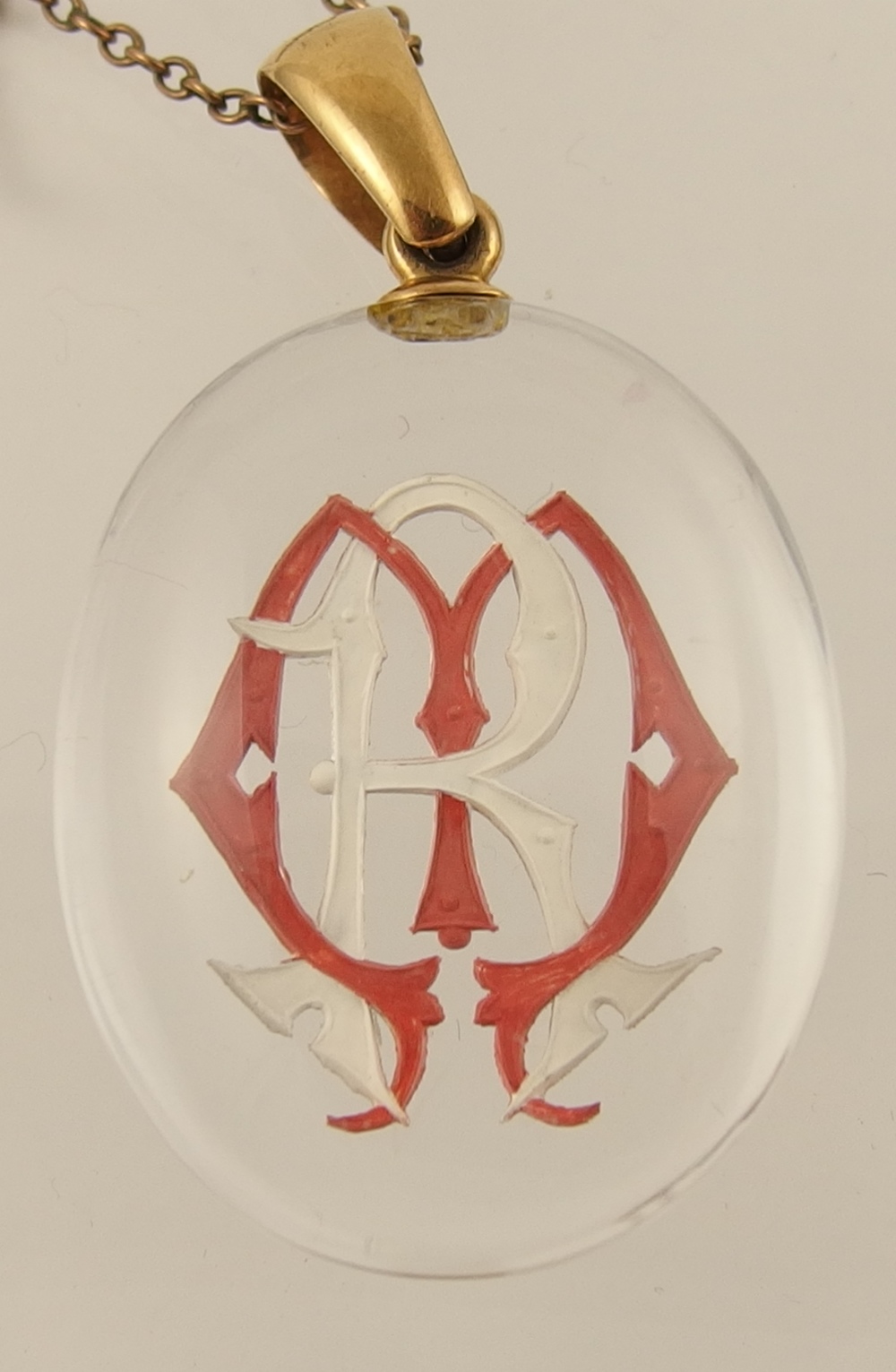 A crystal pendant reverse carved with a monogram in gothic letters MR picked out in red and white,