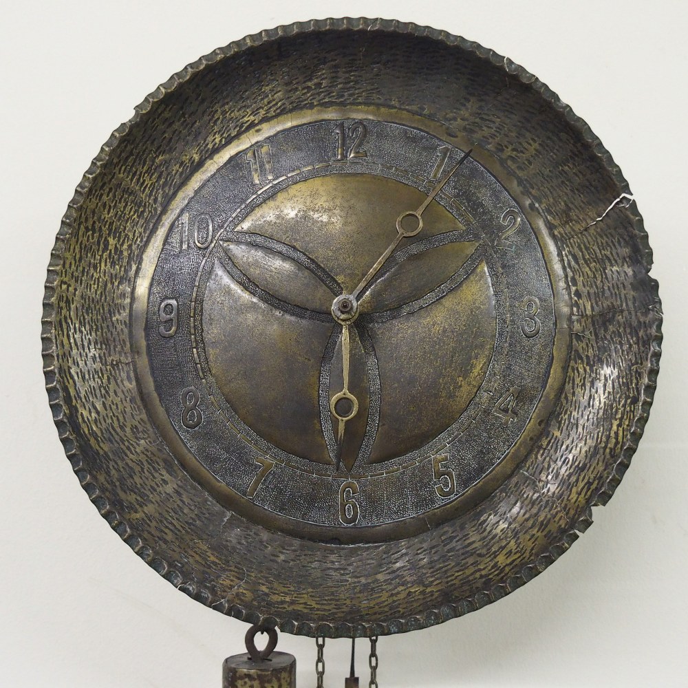 An Arts and Crafts hammered brass `Wag at the Wa` wall clock in the manner of Archibald Knox,