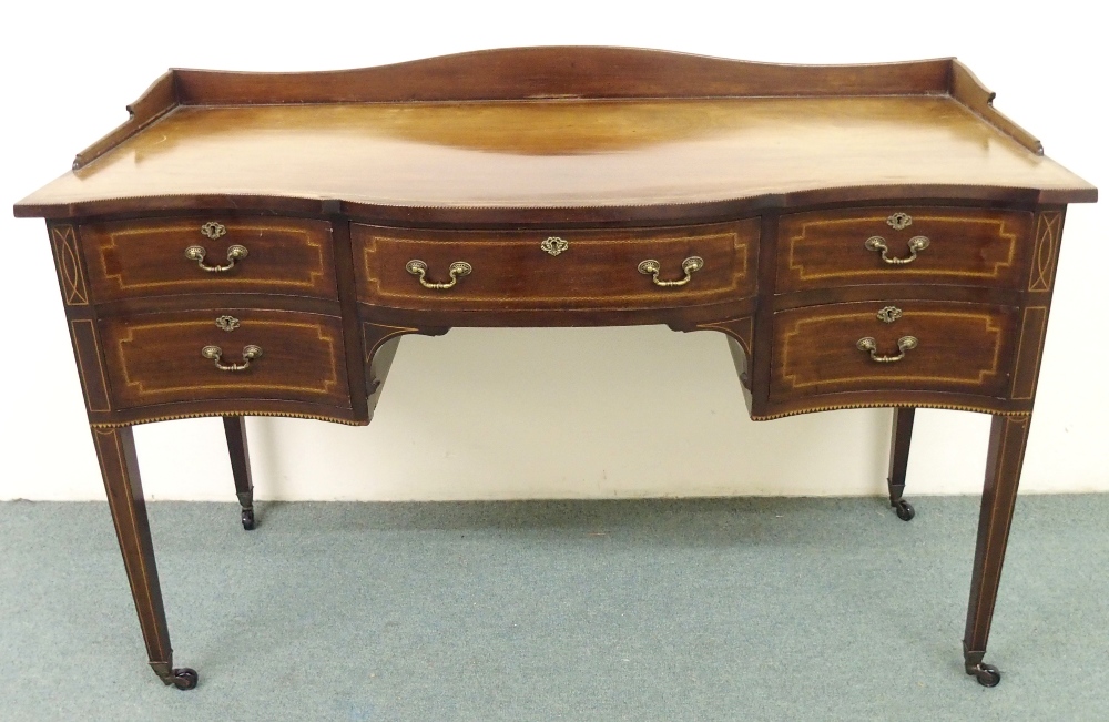 A Sheraton Revival mahogany inlaid desk having a gallery back above a serpentine shaped front,