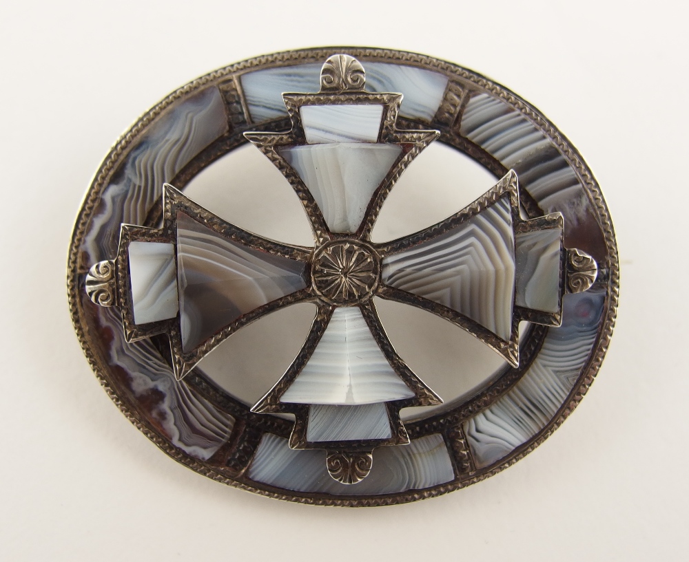 A Scottish agate brooch set with carved banded grey lace agates to the engraved silver border,