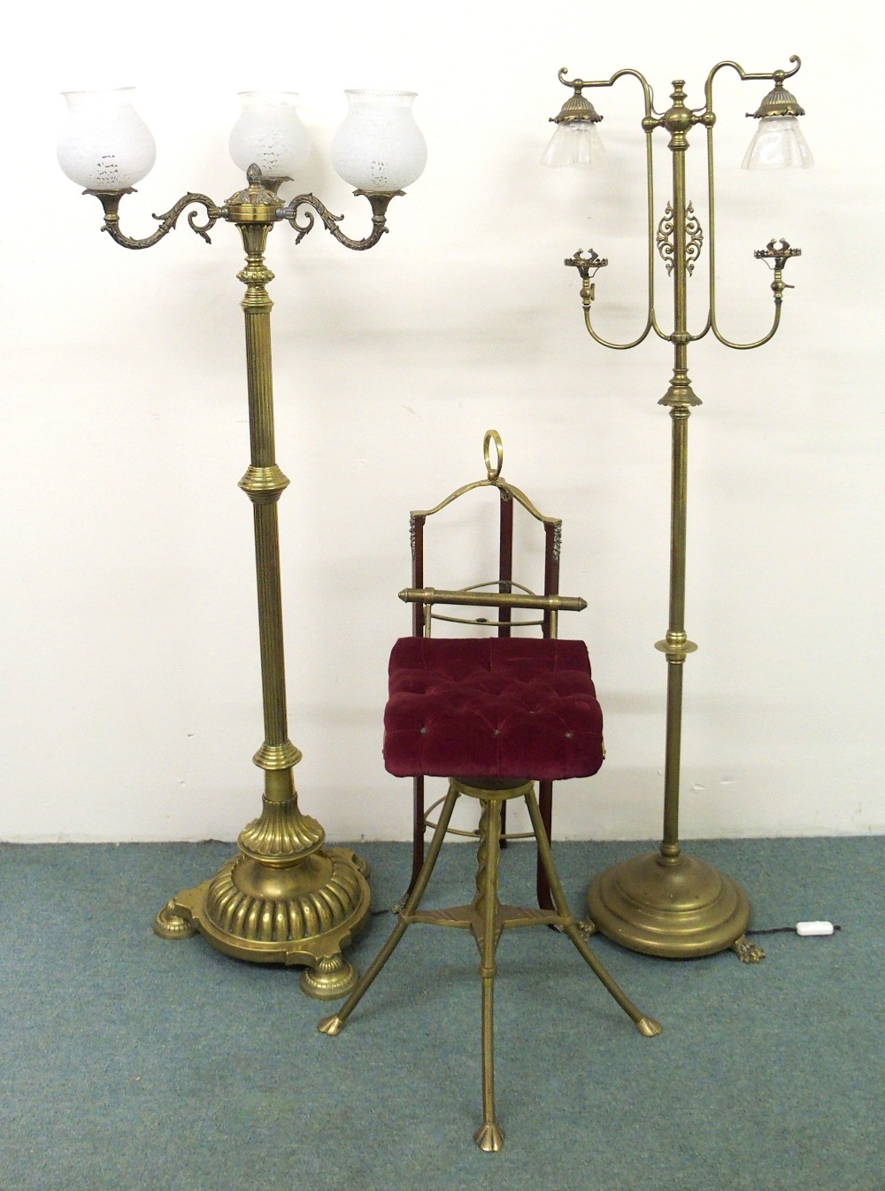 Two late Victorian brass floor lamps having glass shades, raised on circular bases, also with a