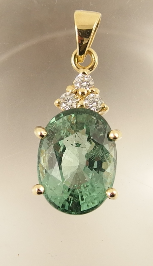 A diamond and tourmaline pendant the tourmaline of greenish blue G/H, clarity commercial S1, of oval