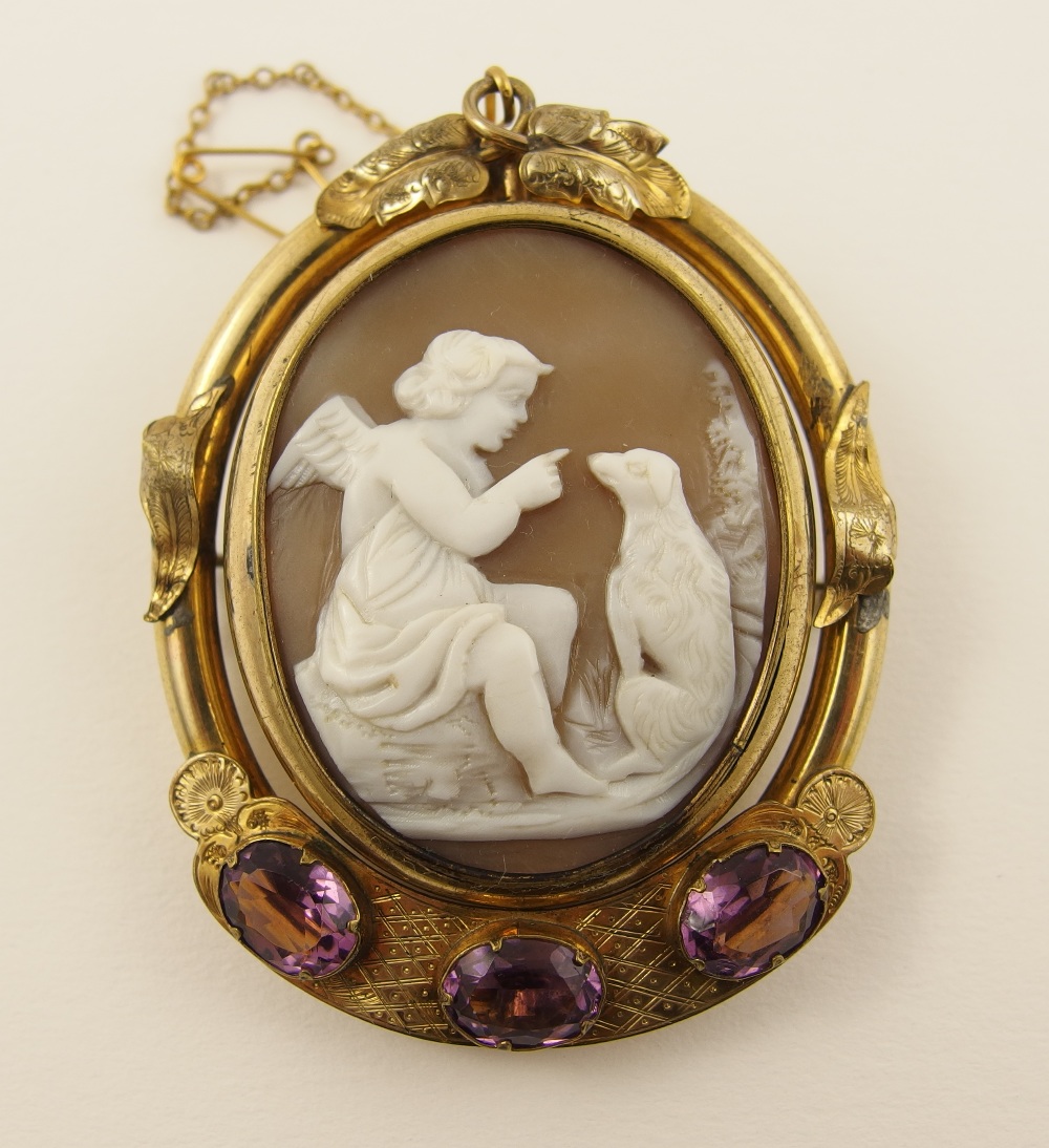 A Shell cameo of a cherub and a dog in a decorative pinchbeck mount with purple glass gem stones,