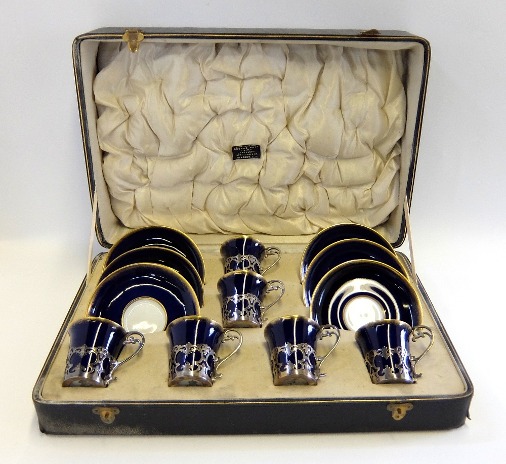 Six boxed Aynsley coffee cans and saucers, the cans in silver holders, marked London 1924