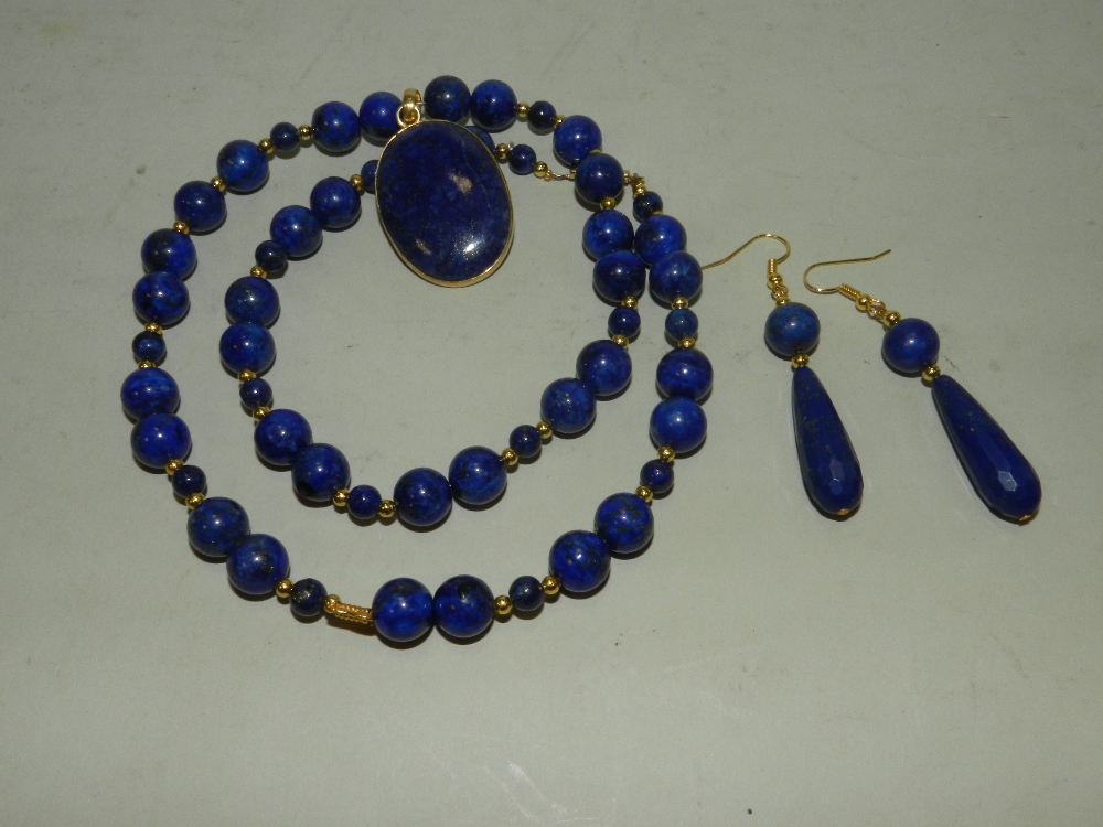 A lapis lazuli pendant on bead necklace with a pair of lapis lazuli drop earrings.