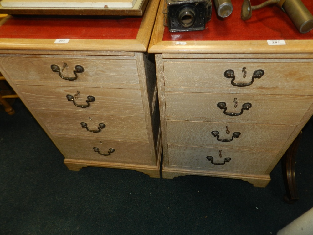 A pair of modern limed oak four drawer cabinets with leather inset tops.