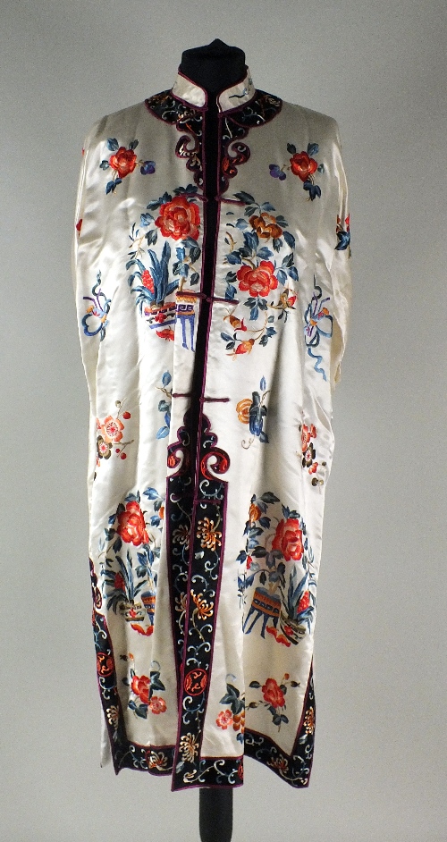 A Chinese silk robe, 20th century, with a white background and black borders, embroidered with