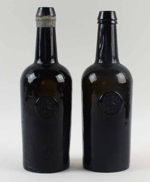 A pair of sealed cylinder black glass wine bottles, late 18th/early 19th century, with applied