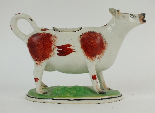 A Staffordshire cow creamer, 19th century, with russet coloured body, set on oval naturalistic