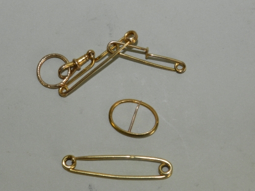 An 18ct gold safety pin together with an 18ct rolled gold double pin and a white metal oval pin