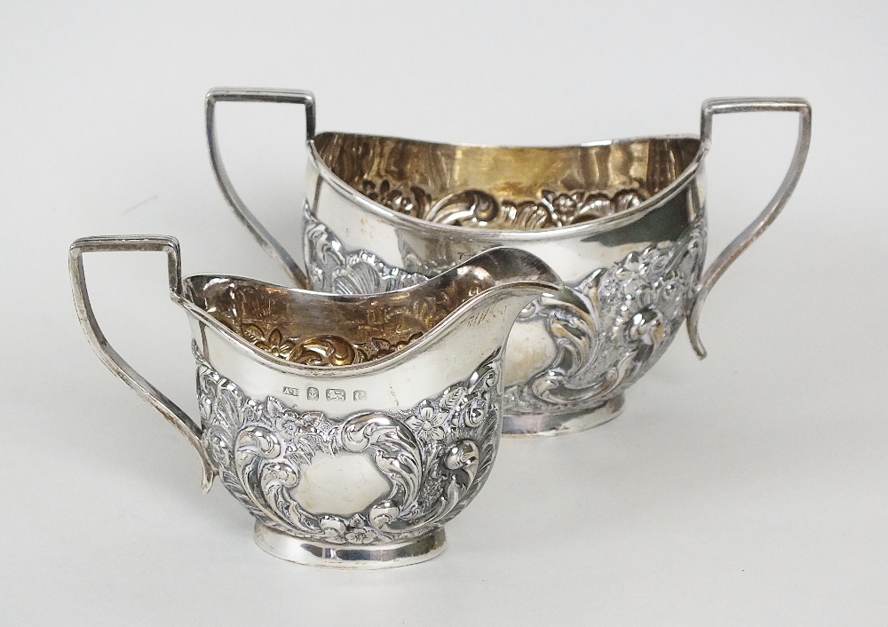 An Edwardian silver sugar bowl and cream jug, AF, Birmingham 1902, each piece with embossed floral