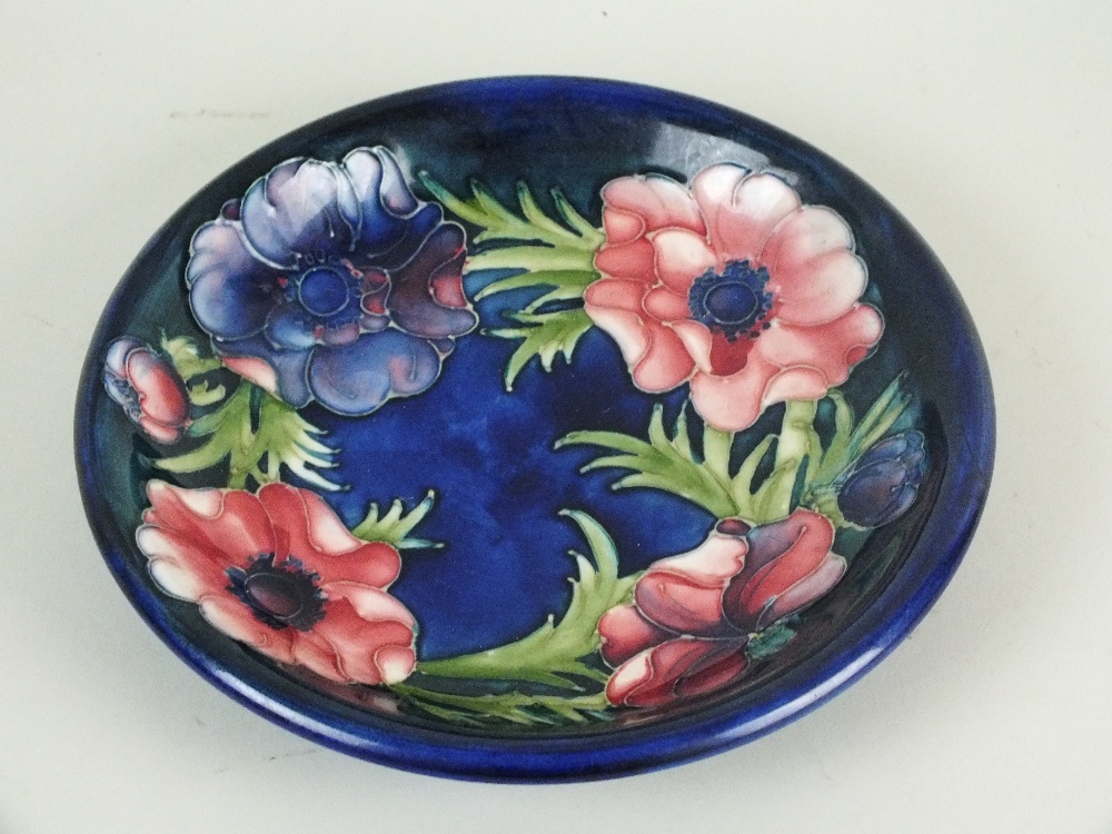 A Moorcroft pottery plate in the Anemone design against a dark blue/green ground, circa 1940s-50s,