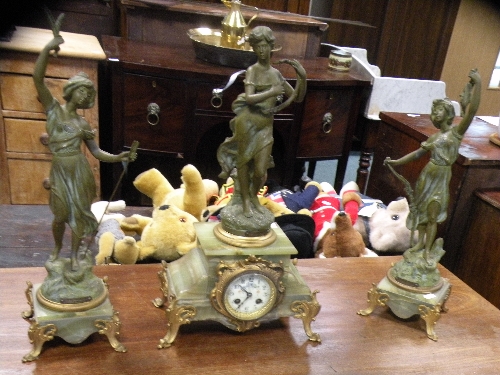 A bronzed spelter and onyx clock garniture mounted with figures for Autumn, Music and Hunting on