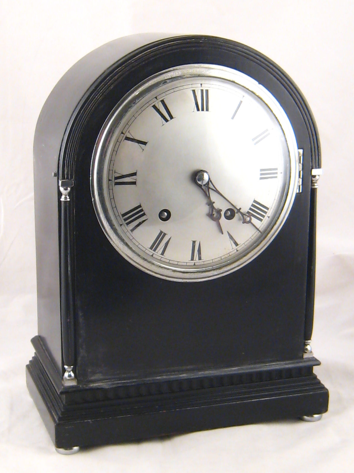 A handsome ebonised mantel clock with domed case, silvered dial and chromium plated mounts on