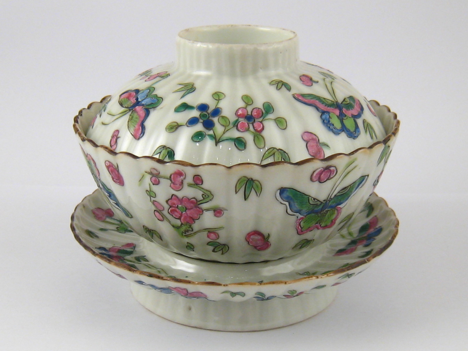 A Chinese ceramic tea bowl, cover and stand, with butterflies in overglaze enamels.