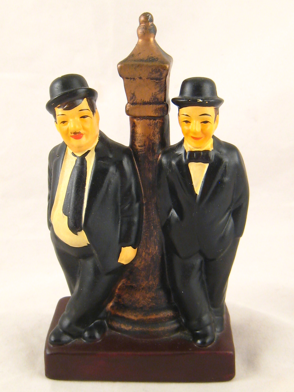 A painted ceramic group of Laurel and Hardy by a lamp post.Ht. 17cm.