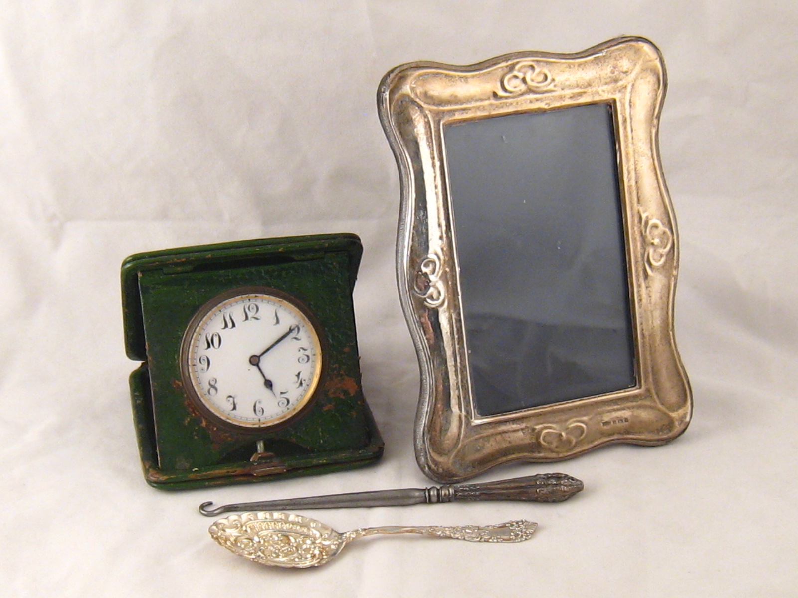 A travelling clock in stand up green leather case, c.1920, a silver faced photo frame, 13x18cms ,a