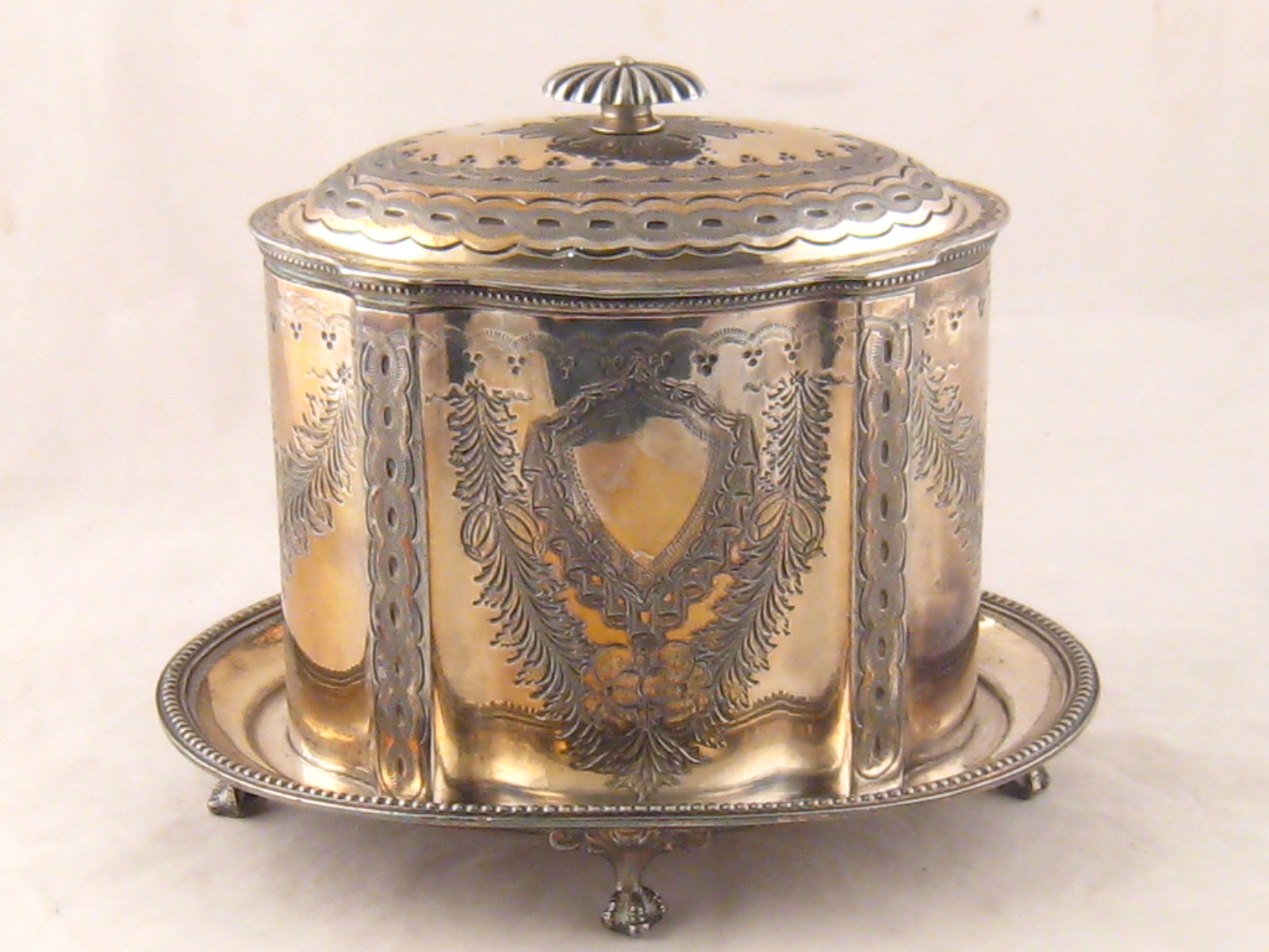 A Victorian silver plated shaped oval biscuit barrel on integral stand with paw feet. 16x22cm.