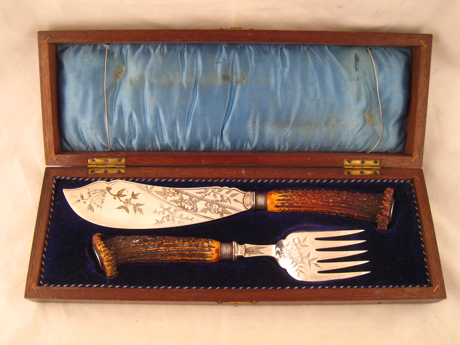 A pair of silver plated fish servers with antler horn handles, the blades engraved in the