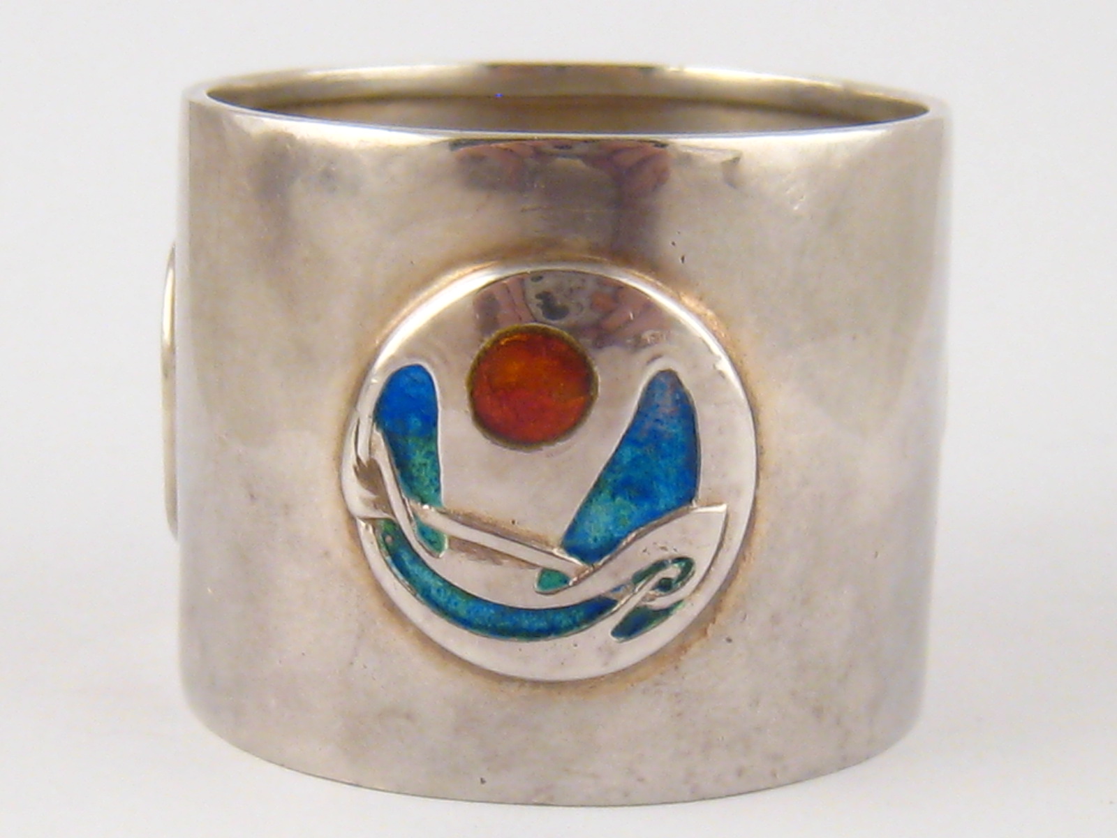 A Liberty & Co. Arts and Crafts silver napkin ring with three enamel appliques, attributed to