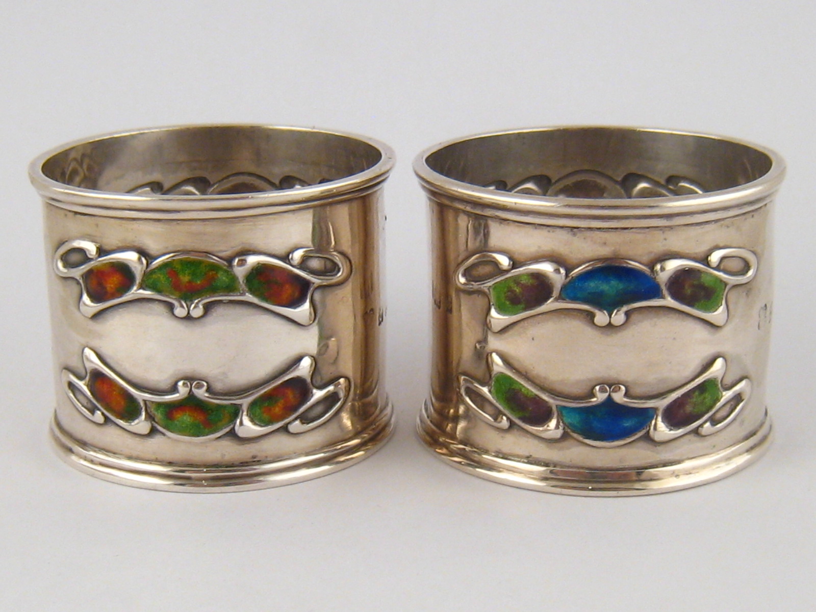 A pair of Liberty &Co. Arts and Crafts silver napkin rings with two double shaded enamel appliques