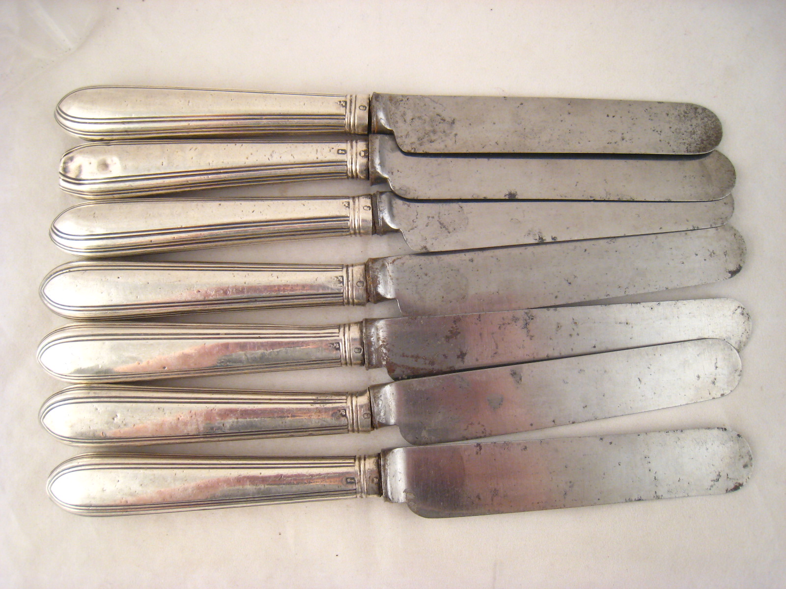 A set of six Georgian silver handled table knives with steel blades, the handles Old English