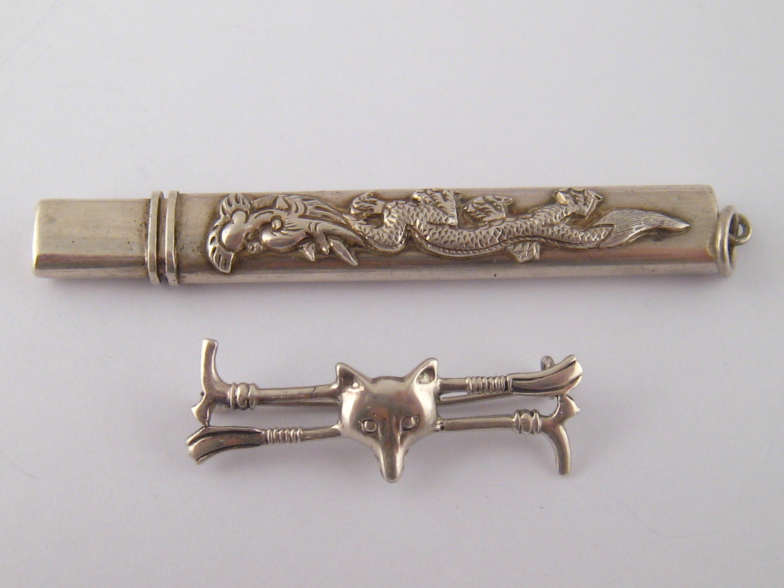 A Chinese white metal pencil case with suspensory loop and dragon applique and a white metal fox