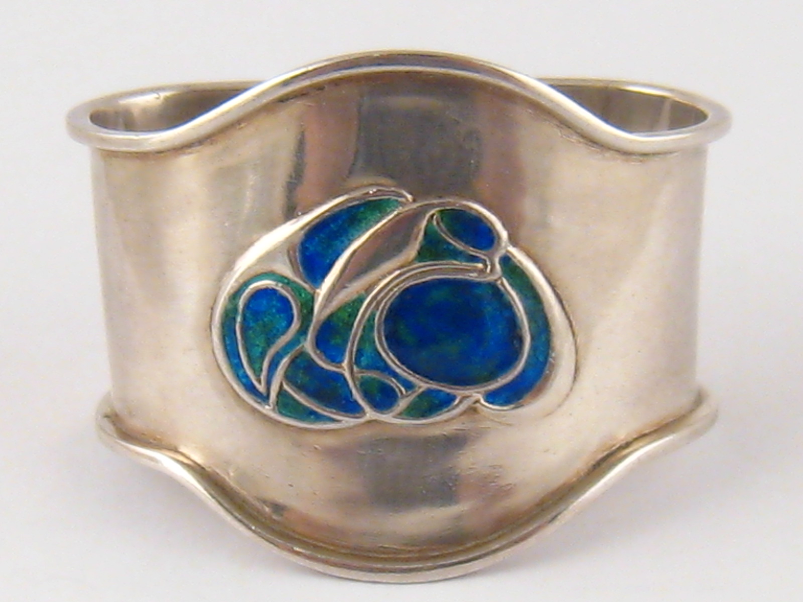 A Liberty &Co. Arts and Crafts silver shaped D napkin ring with shaded turquoise enamel entwined