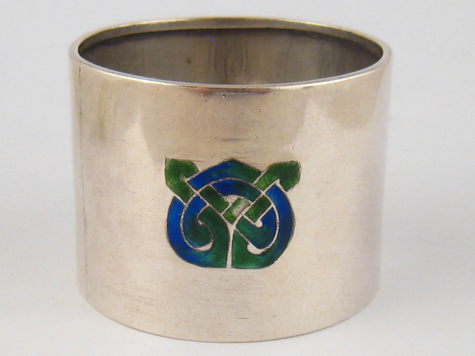 A Liberty And Co. Arts and Crafts silver napkin ring with three shaded enamel appliques,