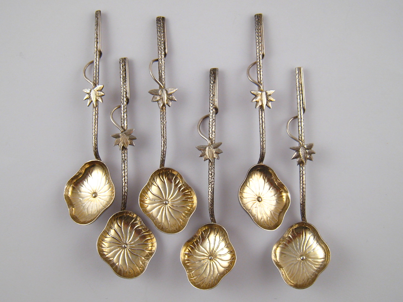 A set of six Chinese white metal (tests silver) teaspoons with stylised lotus bowls and stems.