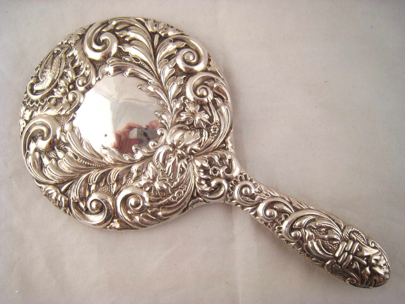 An ornately embossed silver backed hand mirror, Birmingham 1996.
