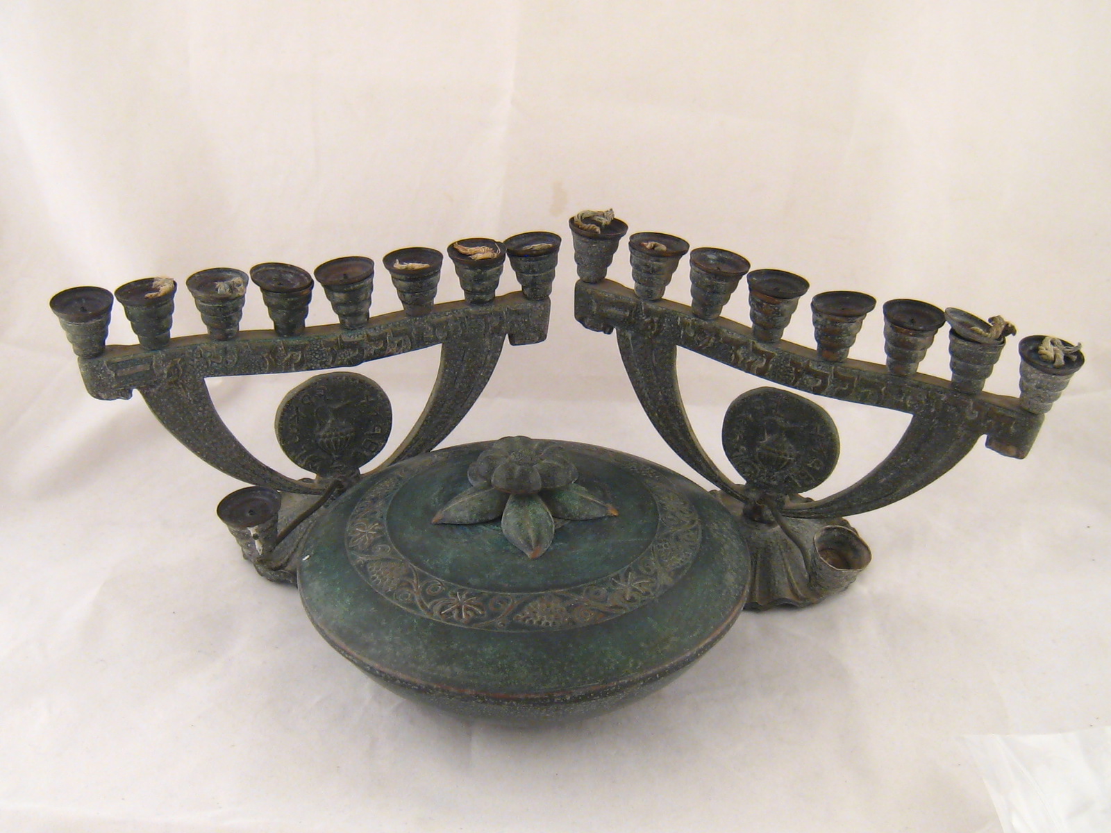 Two brass chanukia, both complete with covers and wicks, and a covered bowl, 18cm. dia.