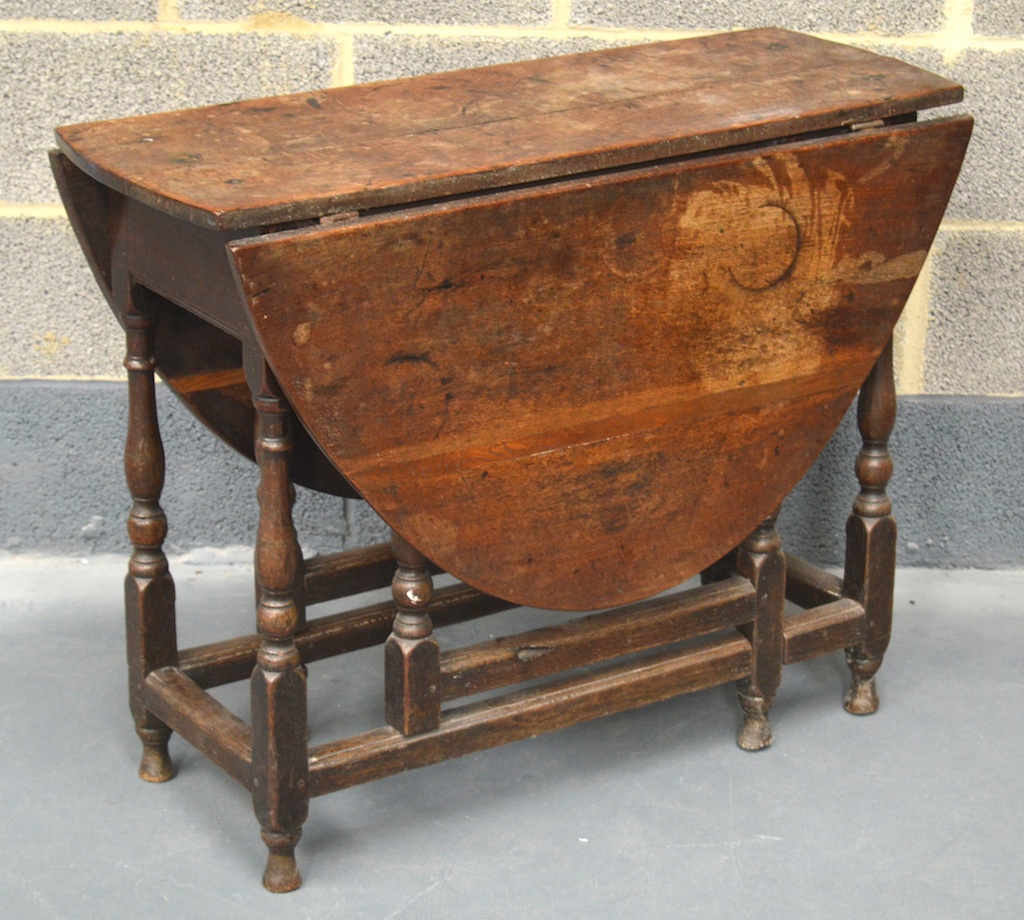 A 17TH/18TH CENTURY CARVED OAK DROP LEAF OCCASIONAL TABLE with twin plank central top and oval