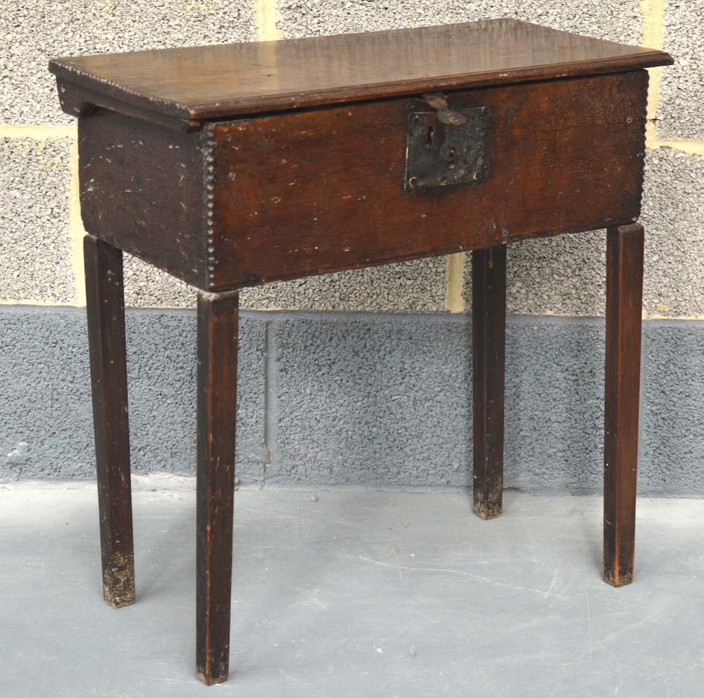 A 17TH CENTURY WEST COUNTRY CARVED OAK BOX upon later legs, with ridged edges to top and sides,