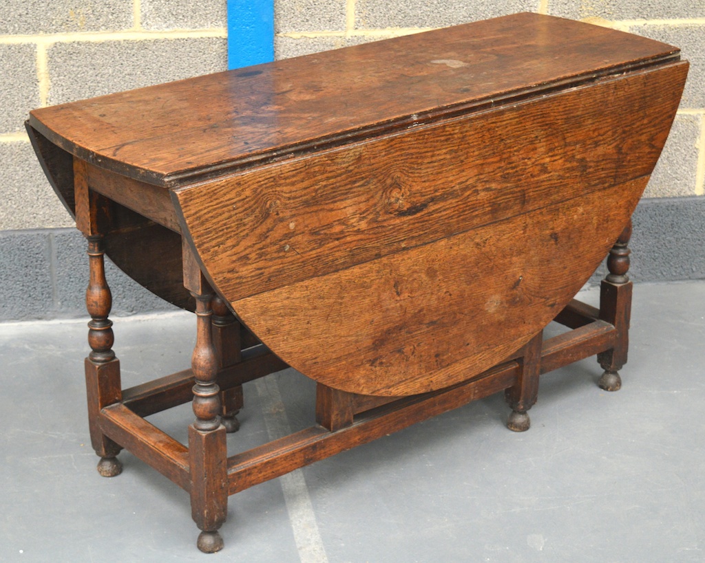 AN 18TH CENTURY CARVED OAK DROP LEAF DINING TABLE with twin plank central top and oval side